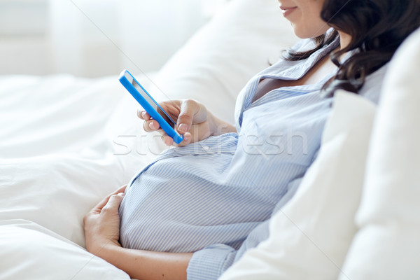 Donna incinta smartphone letto gravidanza maternità Foto d'archivio © dolgachov