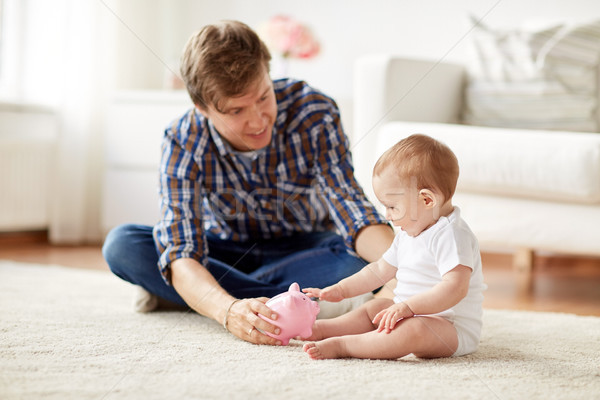 Szczęśliwy ojciec baby banku piggy domu rodziny Zdjęcia stock © dolgachov