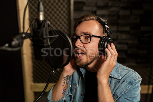 man with headphones singing at recording studio Stock photo © dolgachov