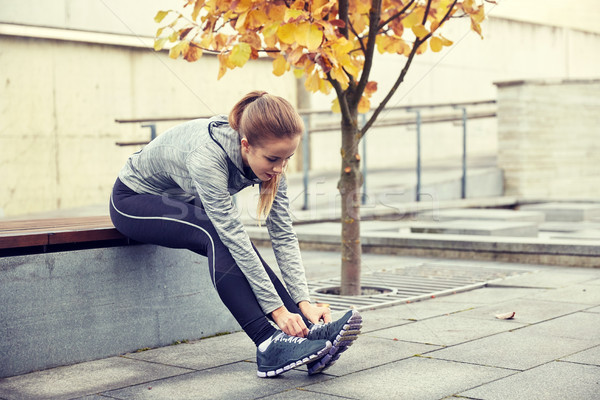 happy young sporty woman tying shoelaces outdoors Stock photo © dolgachov