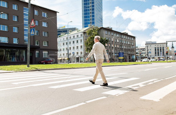 senior man walking along city crosswalk Stock photo © dolgachov