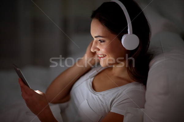 Kobieta smartphone słuchawki bed technologii wypoczynku Zdjęcia stock © dolgachov