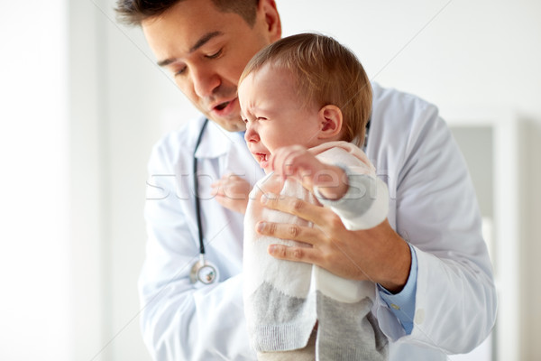 doctor or pediatrician with crying baby at clinic Stock photo © dolgachov