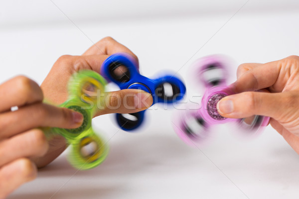 Stock photo: close up of hands playing with fidget spinners