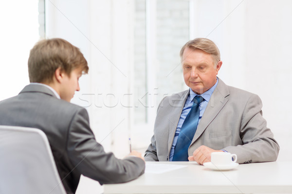 older man and young man signing papers in office Stock photo © dolgachov