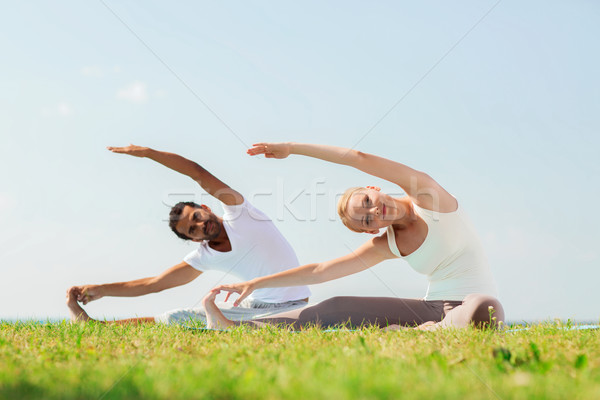 Stock photo: smiling couple making yoga exercises outdoors