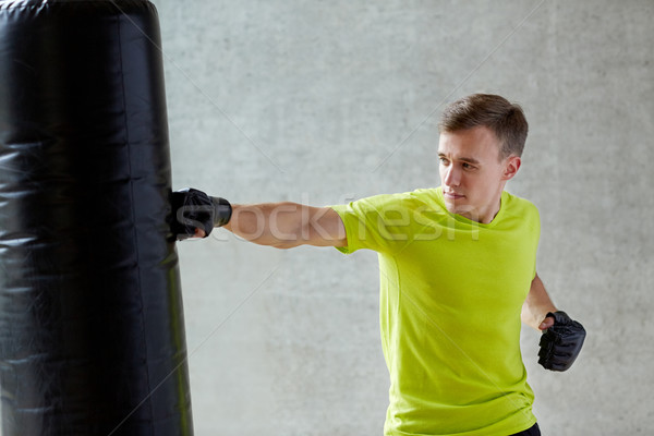 Stock photo: young man in gloves boxing with punching bag