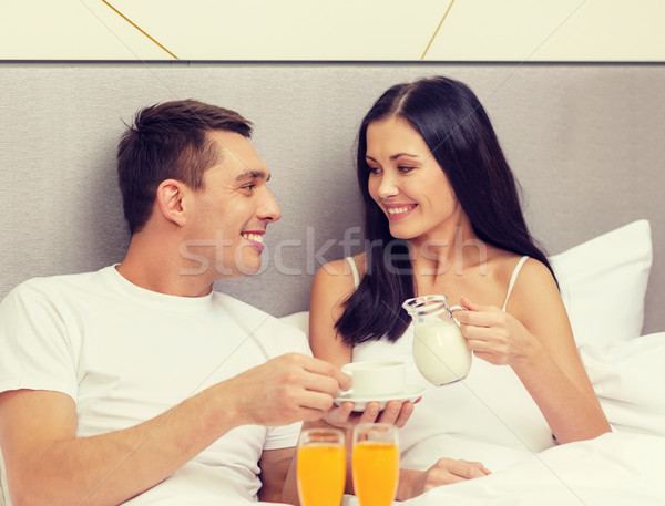 Stock photo: smiling couple having breakfast in bed in hotel