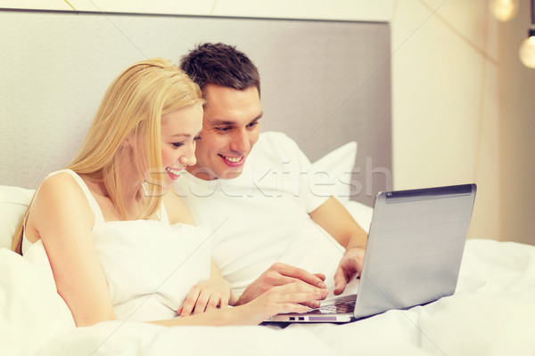 smiling couple in bed with laptop computer Stock photo © dolgachov