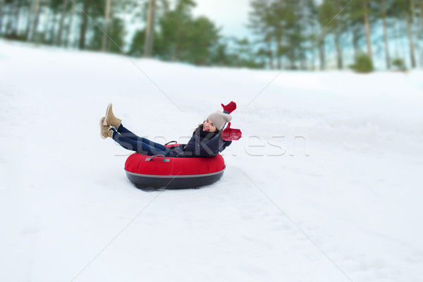 Stock photo: happy teenage girl sliding down on snow tube