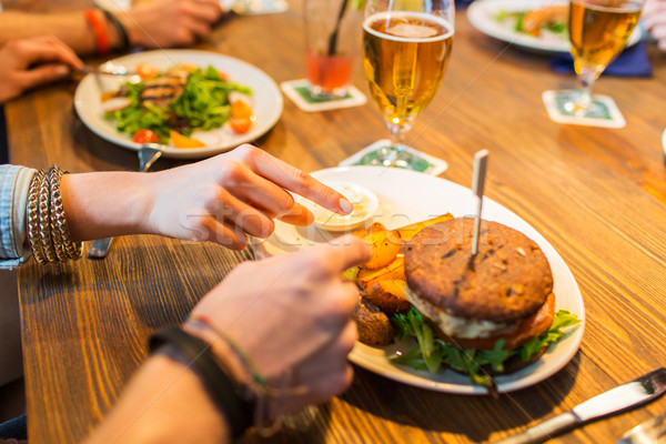 close up of friends hands sharing burger at bar Stock photo © dolgachov