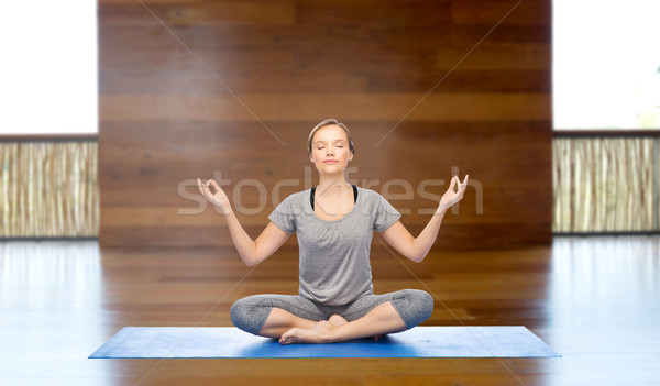 Stock photo: woman making yoga meditation in lotus pose on mat