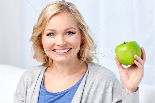 happy middle aged woman with green apple at home Stock photo © dolgachov