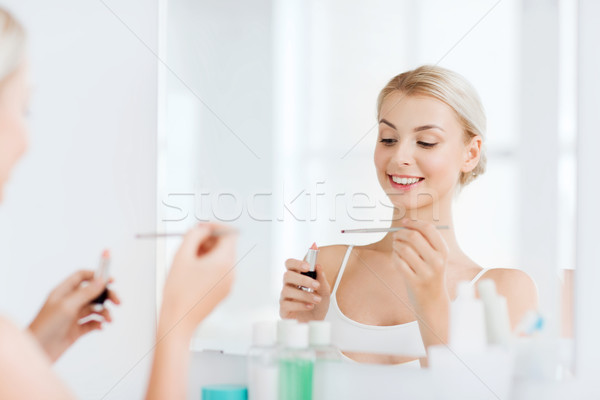 Stock photo: woman with lipstick applying make up at bathroom