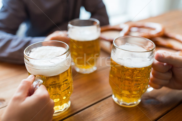 Stock photo: close up of hands with beer mugs at bar or pub