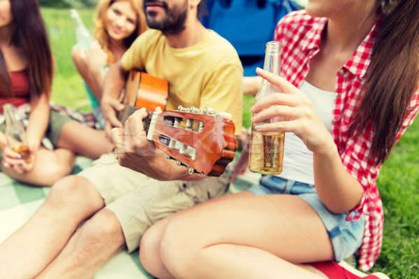 happy friends with drinks and guitar at camping Stock photo © dolgachov