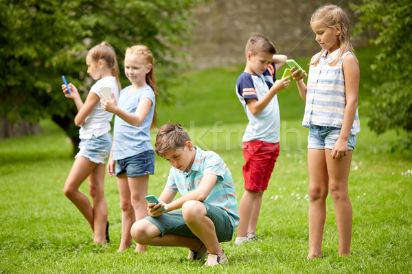 kids with smartphones playing game in summer park Stock photo © dolgachov