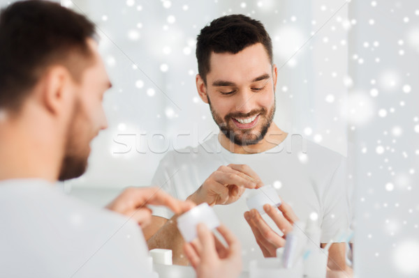 happy young man applying cream to face at bathroom Stock photo © dolgachov