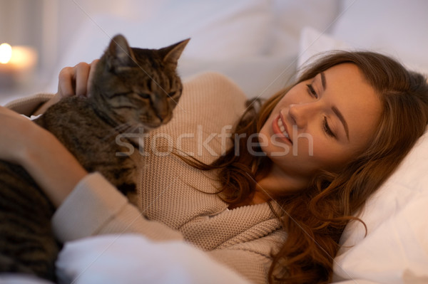 happy young woman with cat lying in bed at home Stock photo © dolgachov