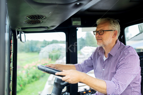 senior man driving tractor at farm Stock photo © dolgachov