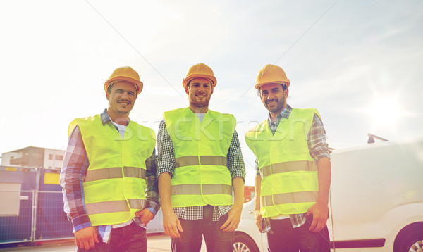 happy male builders in high visible vests outdoors Stock photo © dolgachov