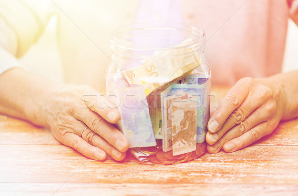 close up of senior woman with money in glass jar Stock photo © dolgachov