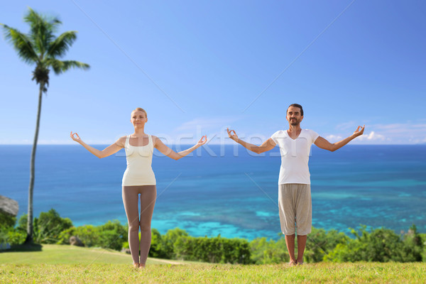 happy couple making yoga exercises on beach Stock photo © dolgachov