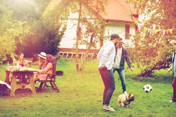 friends playing football with dog at summer garden Stock photo © dolgachov