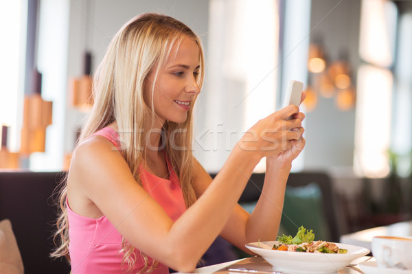 happy woman with smartphone eating at restaurant Stock photo © dolgachov