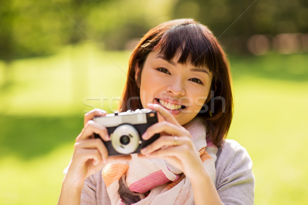 Stock photo: happy young asian woman with film camera outdoors