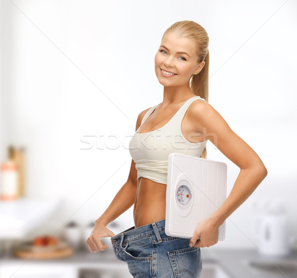 Glimlachende vrouw tonen groot pants schalen Stockfoto © dolgachov