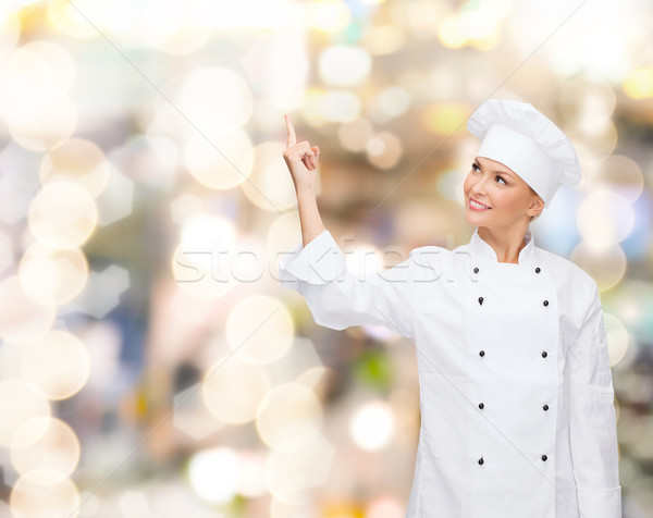 smiling female chef pointing finger to something Stock photo © dolgachov