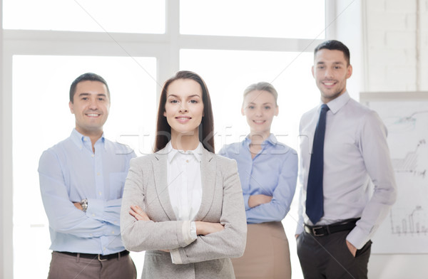 smiling businesswoman in office with team on back Stock photo © dolgachov