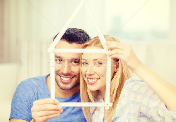 smiling couple with house from measuring tape Stock photo © dolgachov