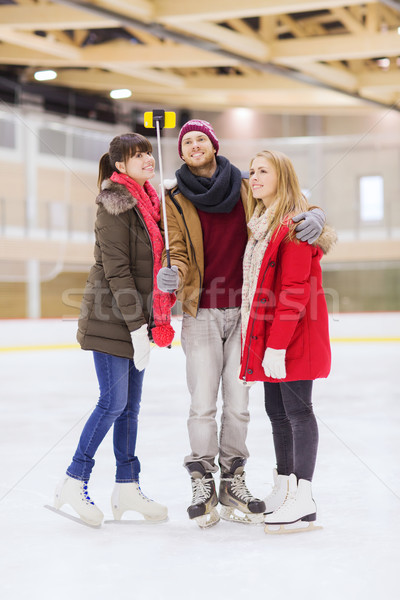 Stock photo: happy friends taking selfie on skating rink