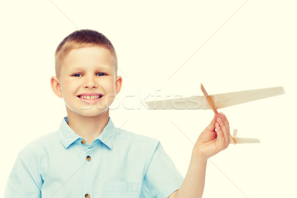 Stock photo: smiling little boy holding a wooden airplane model