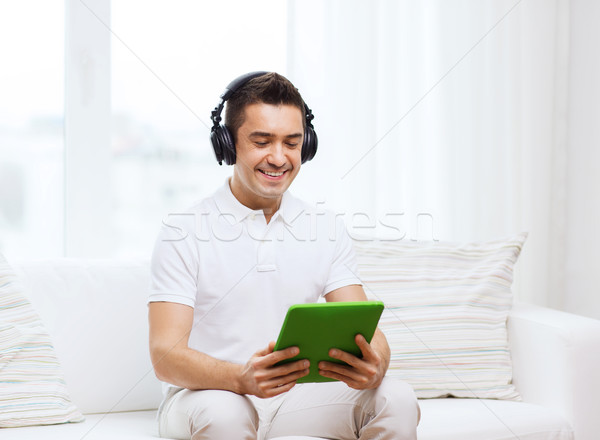 smiling man with tablet pc and headphones at home Stock photo © dolgachov