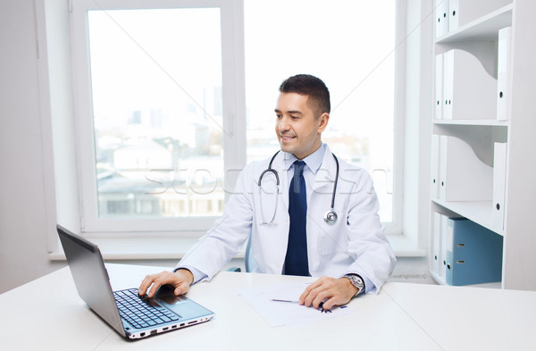 smiling male doctor with laptop in medical office Stock photo © dolgachov