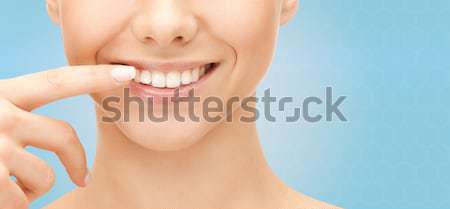 close up of smiling woman face pointing to teeth Stock photo © dolgachov