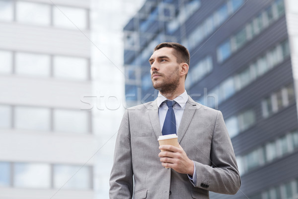 young serious businessman with paper cup outdoors Stock photo © dolgachov