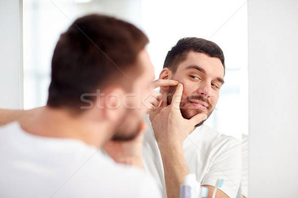 man squeezing pimple at bathroom mirror Stock photo © dolgachov