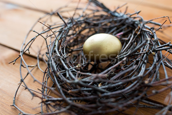 close up of golden easter egg in nest on wood Stock photo © dolgachov