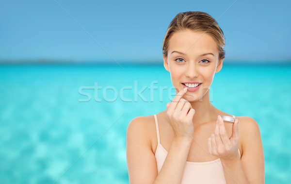 Stock photo: smiling young woman applying lip balm to her lips