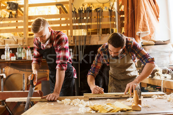 carpenters working with saw and wood at workshop Stock photo © dolgachov
