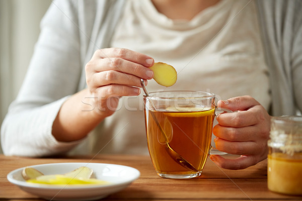 close up of woman adding ginger to tea with lemon Stock photo © dolgachov