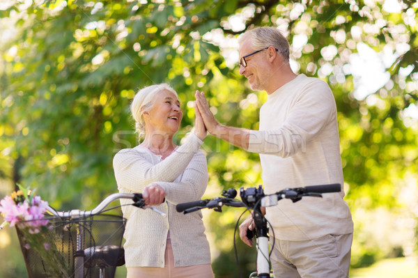 senior couple with bikes making high five at park Stock photo © dolgachov