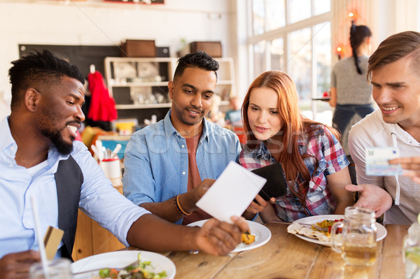 happy friends with money paying bill at restaurant Stock photo © dolgachov