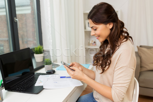 woman with papers and smartphone working at home Stock photo © dolgachov