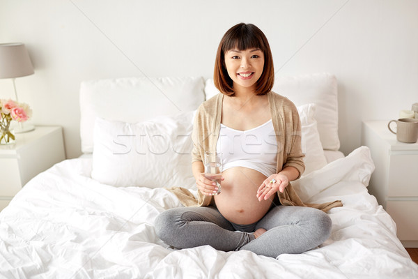 Feliz mulher grávida pílulas cama casa gravidez Foto stock © dolgachov