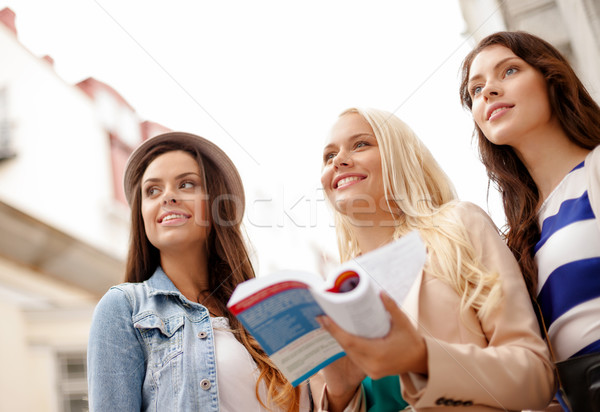 three beautiful girls with tourist book in city Stock photo © dolgachov